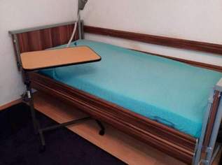 Pflegebett mit Funktionen inklusive Esstisch.